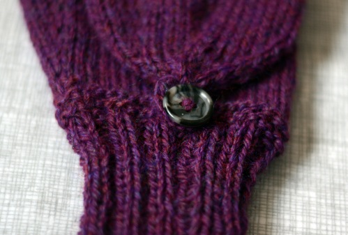 A close detail of a button on one mitten.