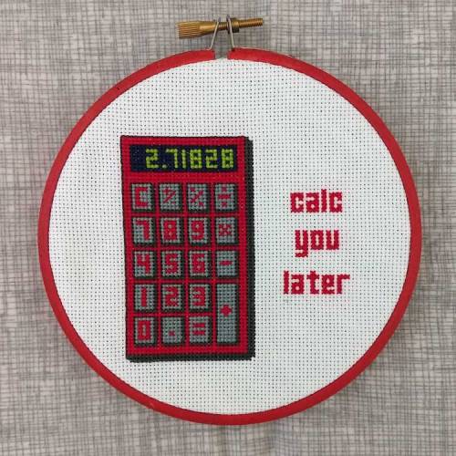 cross stitch in an embroidery hoop on a gray background. The hoop has a cross stitched image of a red calculator, to the right are the words "calc you later"